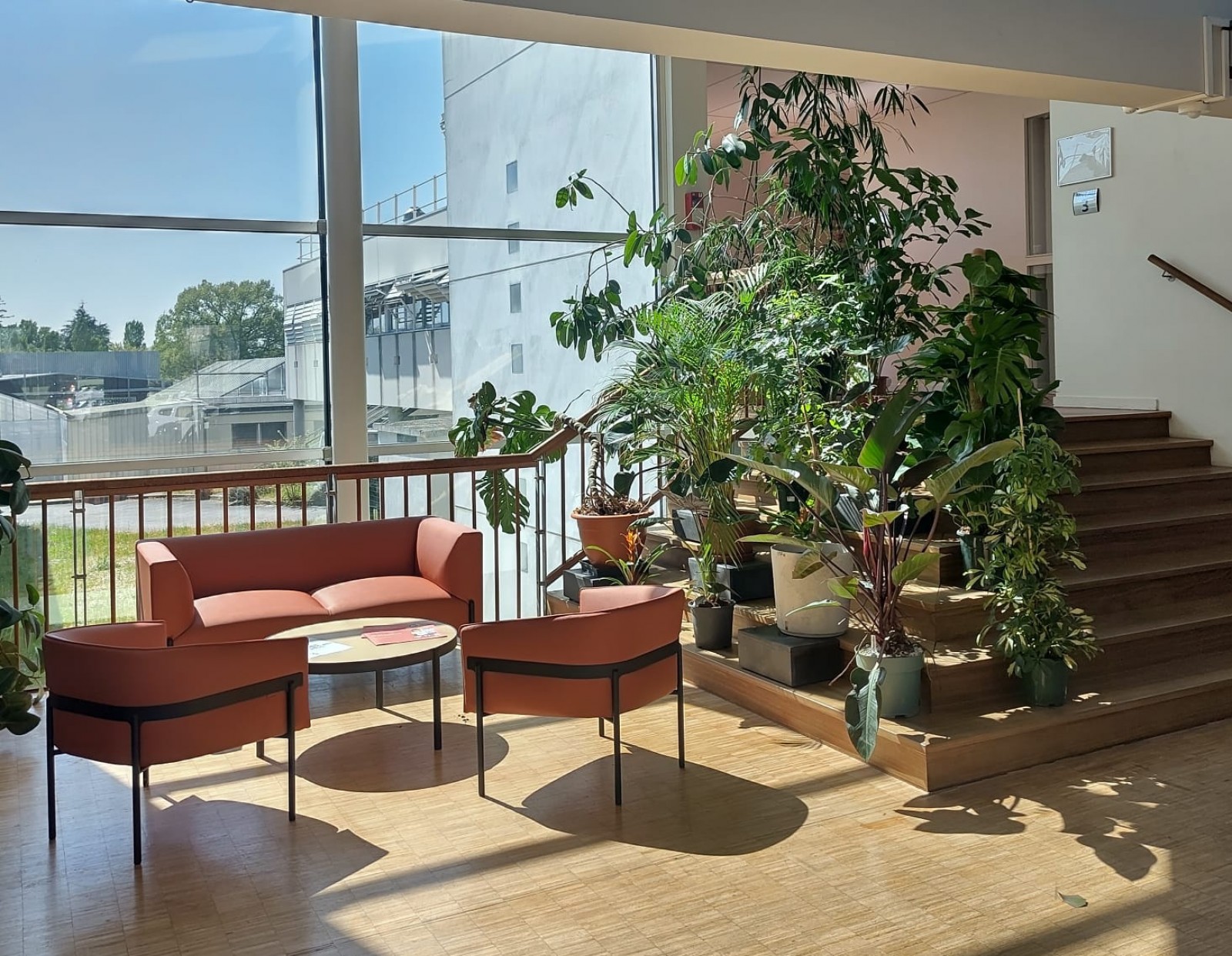 Hall d’accueil INRAE Villenave d’Ornon : canapé design, chauffeuses colorées, plantes vertes pour un espace d’attente chaleureux.